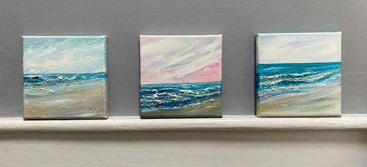 3 square seascape paintings on a narrow ledge