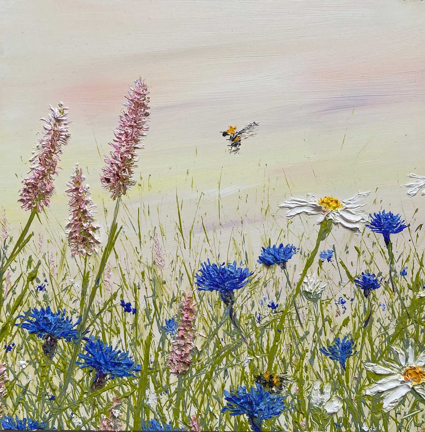 Textured oil painting of a field with bees and wildflowers including blue cornflowers and daisies.