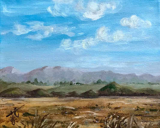 Painting cropped to edge: a landscape with yellowed farmlands in the foreground, hills and mountains in the distance and clouds in the sky. A farmstead is visible among some trees on the hills.